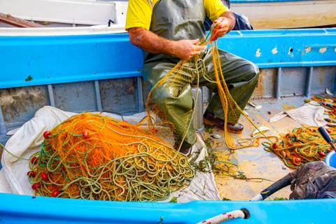 Fisherman is empty fish from net in his small boat Stock Photos
