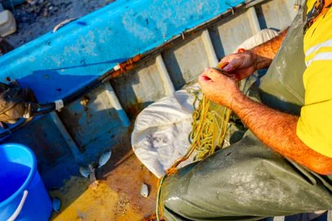 Fisherman is empty fish from net in his small boat Stock Photos