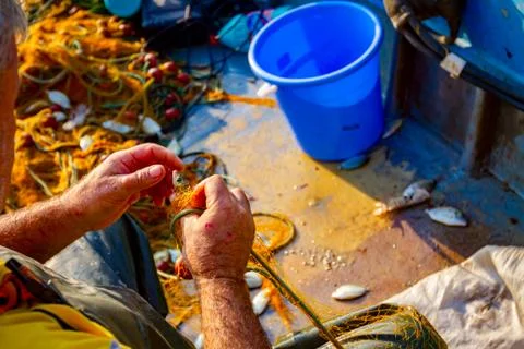 Fisherman is empty fish from net in his small boat Stock Photos