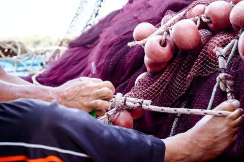 Fisherman is fixing the fish net pull with his foot Stock Photos