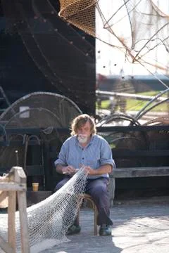 Fisherman fixing his nets Stock Photos