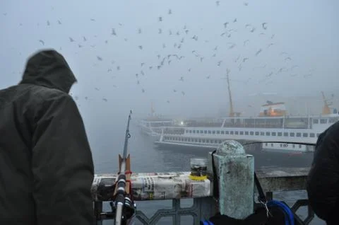 Fisherman in foggy weather on the bridge in Istanbul. Stock Photos