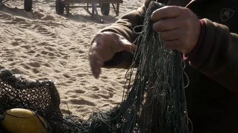 Fisherman folding nets on a sandy beach in Portugal Stock Footage 112893648