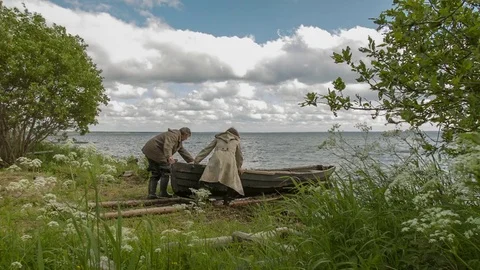 Fisherman With Friend Rowing In Small Old Boat On The River Near Small Village Stock Footage 78775352