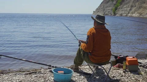 A fisherman with a hat caught a small fish in a bay on the river. Fishing on the Stock Footage 137458368