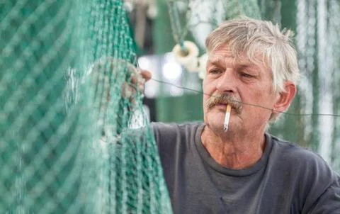 Fisherman mending nets Stock Photos