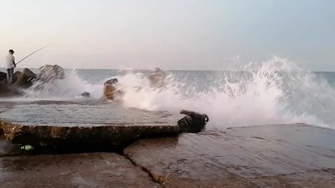 Fisherman on the pier and breaking waves Stock Footage 141034178