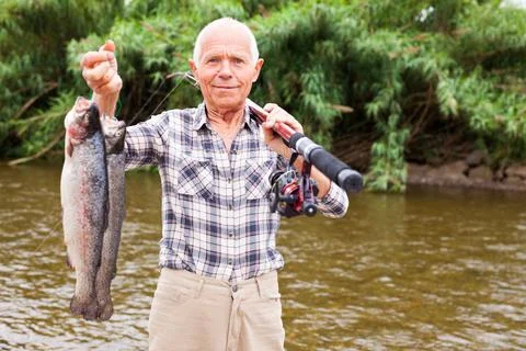 Fisherman posing with catch at riverside Stock-Fotos