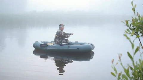 Fisherman preparing the bait on an inflatable boat. Foggy morning on the lake Stock Footage 64586164
