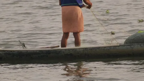 Fisherman pull his net from the water standing in a canoe Stock Footage 305387221