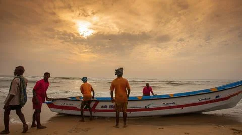 The fisherman pulling the boat in beach at during sunrise golden hour Stock Photos