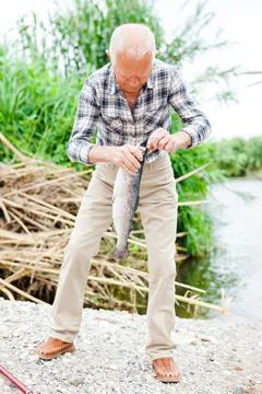 Fisherman pulling fish from river Stock-Fotos