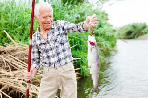 Fisherman pulling fish from river Foto stock