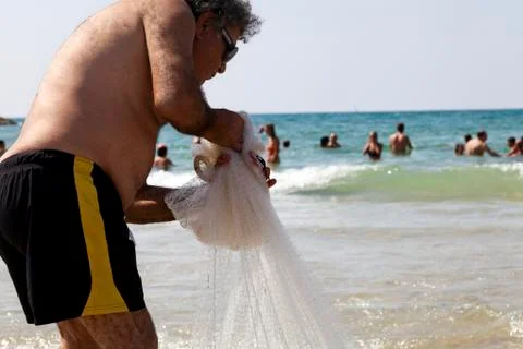 Fisherman pulling net on tel-aviv beach Stock Photos