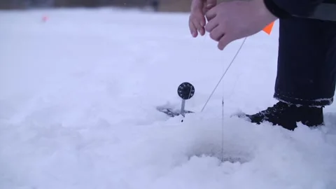Fisherman pulling northern fish from ice fishing hole on frozen lake in winter. Stock Footage 313815181