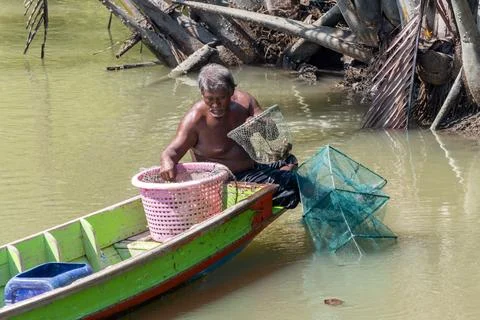 A fisherman pulls a catch from the nets off a tropical coast Foto stock