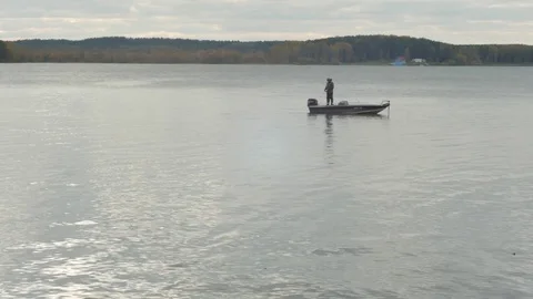 Fisherman pulls a hooked fish on the boat at lake. Fisherman in the boat fishing Stock Footage 73177716