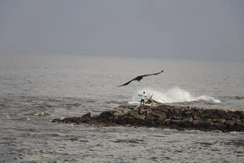 Fisherman on a reef in the rough seas Stock Photos