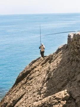 Fisherman on a rock. Stock Photos