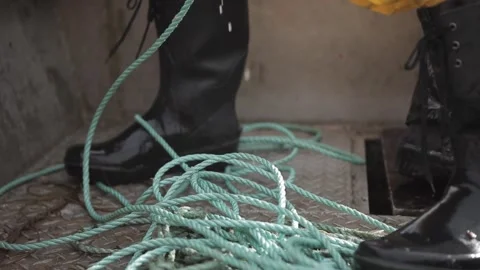 Fisherman in rubber boots on boat pulling out the sea a thread Stock Footage 149657787