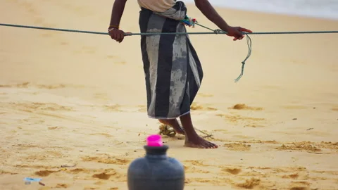 Fisherman in a Sarong Pulling a Net Rope on the Sand Stock Footage 343947357