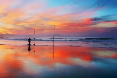 Fisherman silhouette on beach at sunset Stock Photos