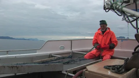 Fisherman sitting down as he untangles his net that is being pulled out of the Stock Footage 93556902