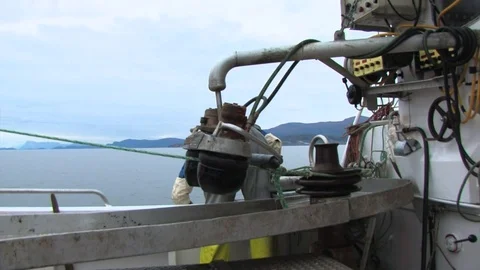 Fisherman sitting down as he untangles his net that is being pulled out of Stock Footage 103530612