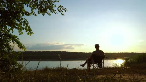 Fisherman sitting by river at sunset Stock Footage 156646620