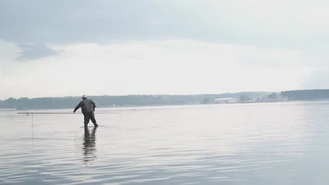 Fisherman standing hip high deep in the sea holding fishing rod action Stock Footage 146269495
