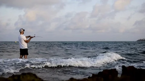 Fisherman standing at the seashore hooks a fish. Stock-Footage 130077099