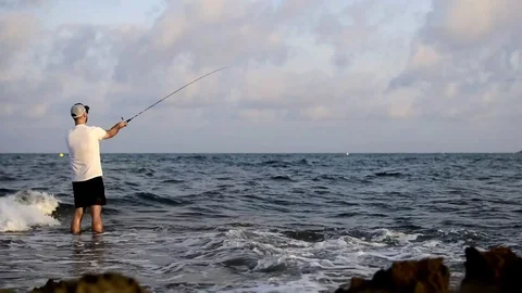 Fisherman standing at the seashore hooks a fish. Vídeos de archivo 130077141