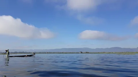 Fisherman stands and dips net and pole in water, shot in motion, Inle Lake Видео 79636326
