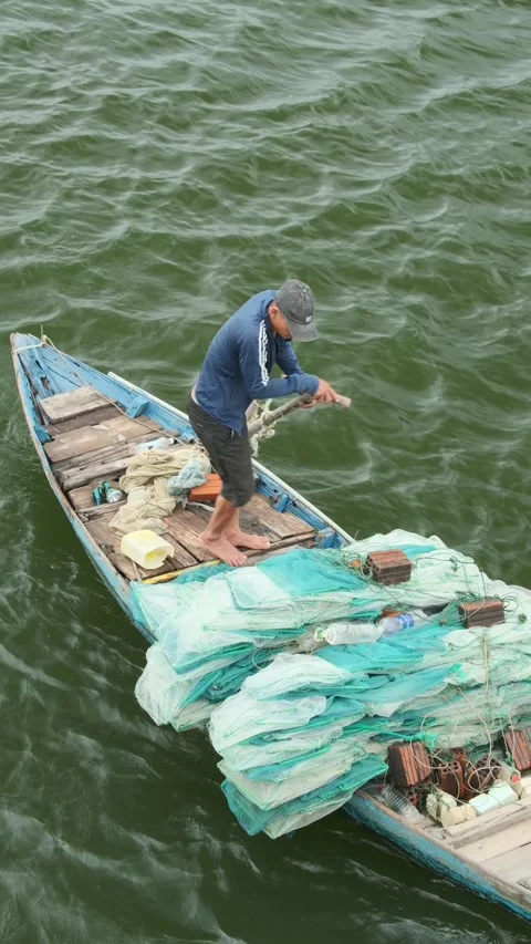 Fisherman stands in small boat, handling nets Vidéo 344718445