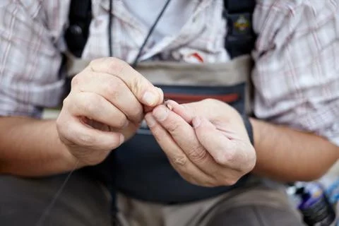 Fisherman threading a small fly onto his line Stock Photos