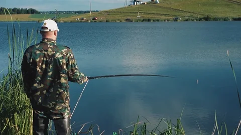 Fisherman wait, then pulls out caught fish Stock Footage 104763570