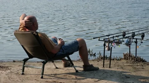 Fisherman waiting to catch a fish with carp fishing equipment near river or lake Video stock 159746816