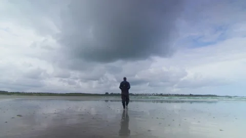A fisherman walks on the beach at low tide, in Brittany, France Stock Footage 229693172