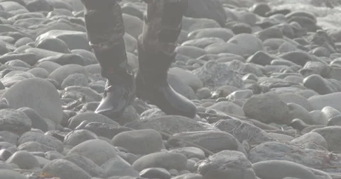 FISHERMAN WALKS ON LARGE RIVERS EDGE STONES Stock Footage 164810622