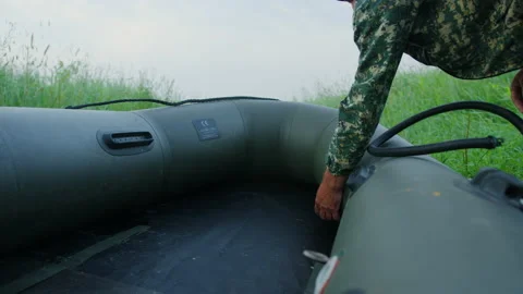 A fisherman while preparing a rubber boat for fishing on the lake shore Stock Footage 219776627