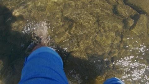 Fisherman without shoes goes through the shallow water on the river close-up Video stock 102913228