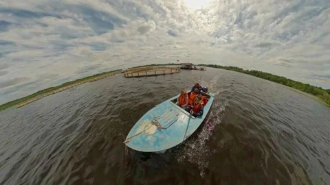 Fishermen in a boat float among the cages for breeding valuable fish breeds at a Stock Footage 274335182