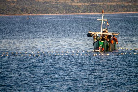 Fishermen on Cinch Ring Boat Pulling Nets that are Spread Stock Photos
