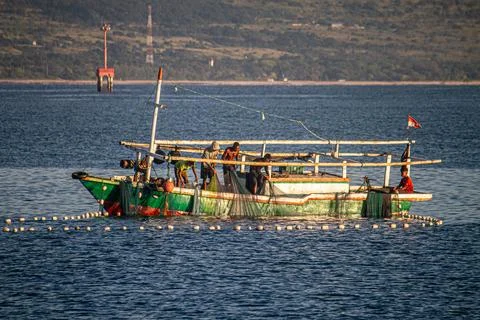 Fishermen on Cinch Ring Boat Pulling Nets that are Spread Stock Photos