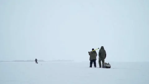 Fishermen go on a winter fishing trip on the ice of a frozen lake. Stock Footage 236558053