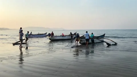 Fishermen pull boats out of the sea, fishing boats on tropical beach Stock Footage 251554788