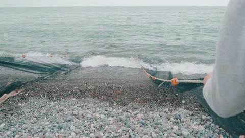Fishermen pull nets from the sea on a beach with dramatic sky on Black sea Stock Footage 196925649