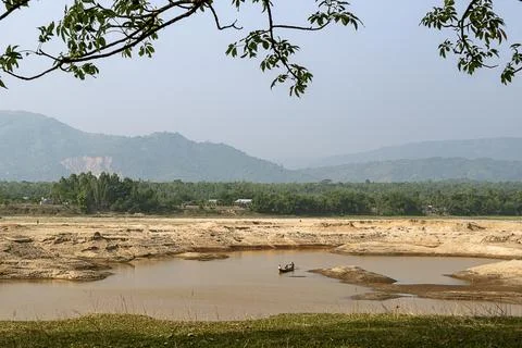 Fishermen Rowing on a Tranquil River with Sandy Banks and Distant Mountains Stock Photos
