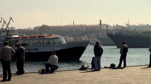 Fishermen settle down along water's edge and catch fish. Video stock 106062314