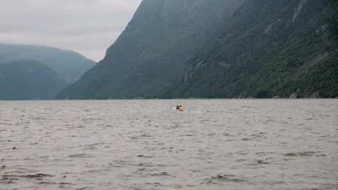 Fishermen in a small boat casting nets in a tranquil Norwegian fjord surrounded Stock Footage 344690712